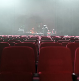 people sitting on red chairs watching a band performing on stage