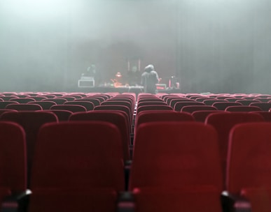 people sitting on red chairs watching a band performing on stage