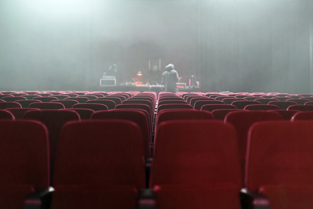 people sitting on red chairs watching a band performing on stage