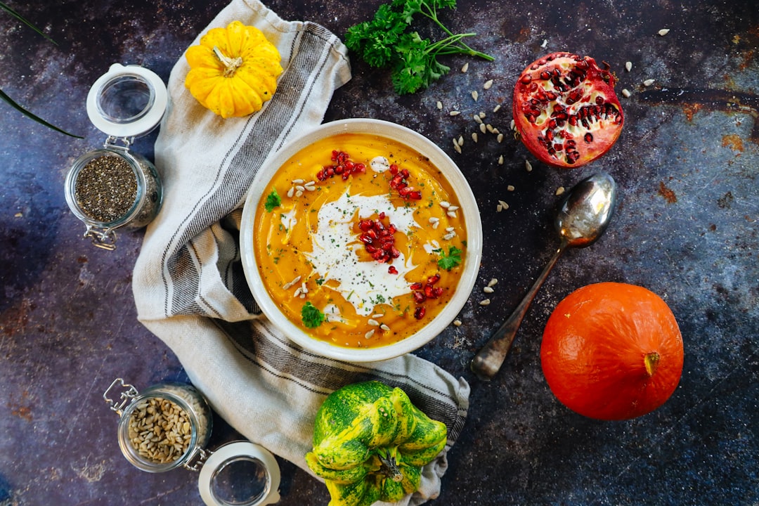 soup with sliced lemon on white ceramic bowl, Creamy Roasted Pumpkin Soup. Very delicious seasonal food dish.