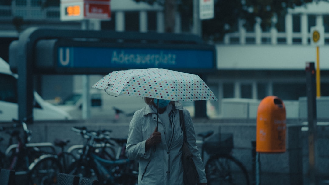 person in gray coat holding umbrella