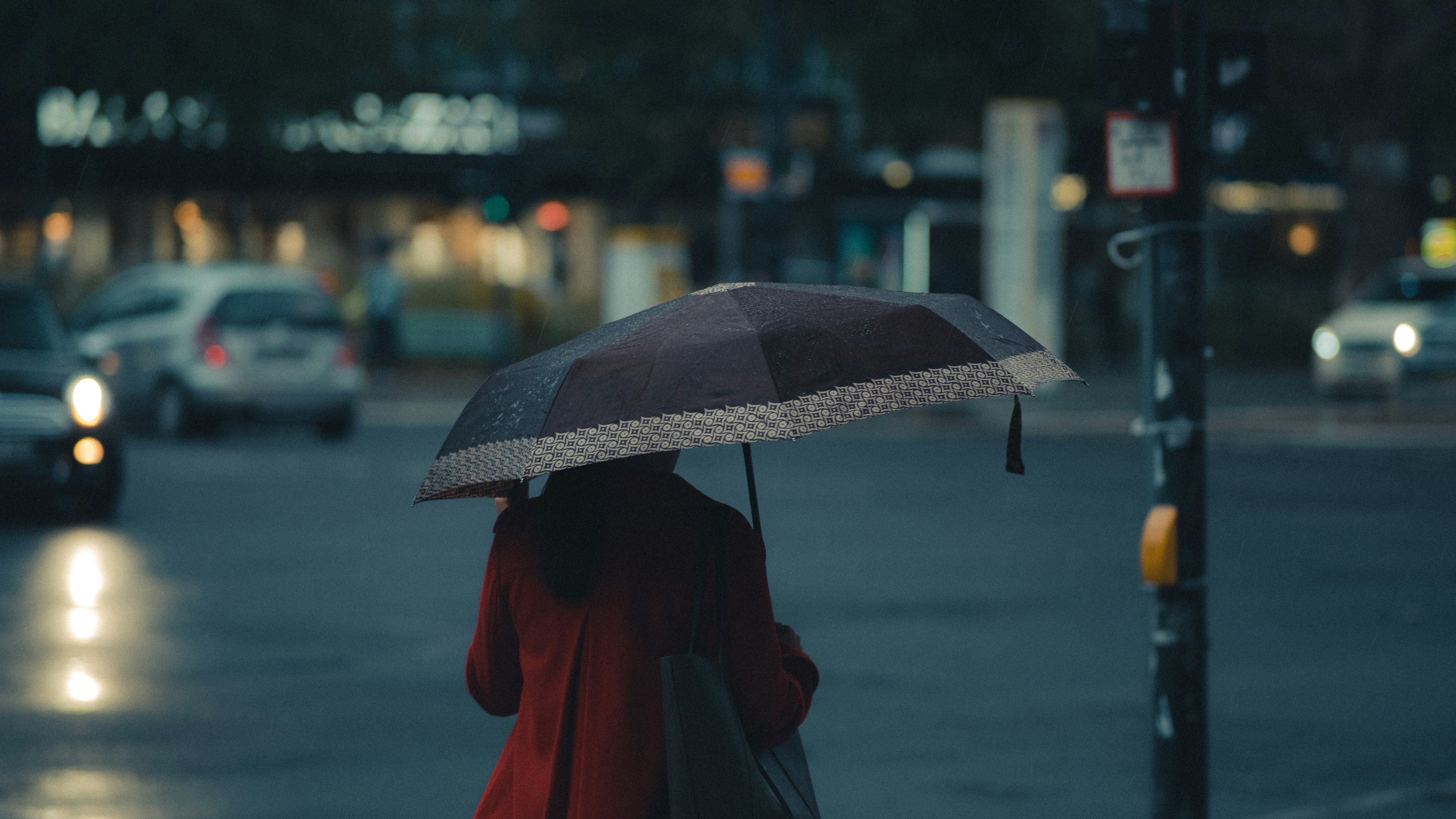 person in red coat holding umbrella