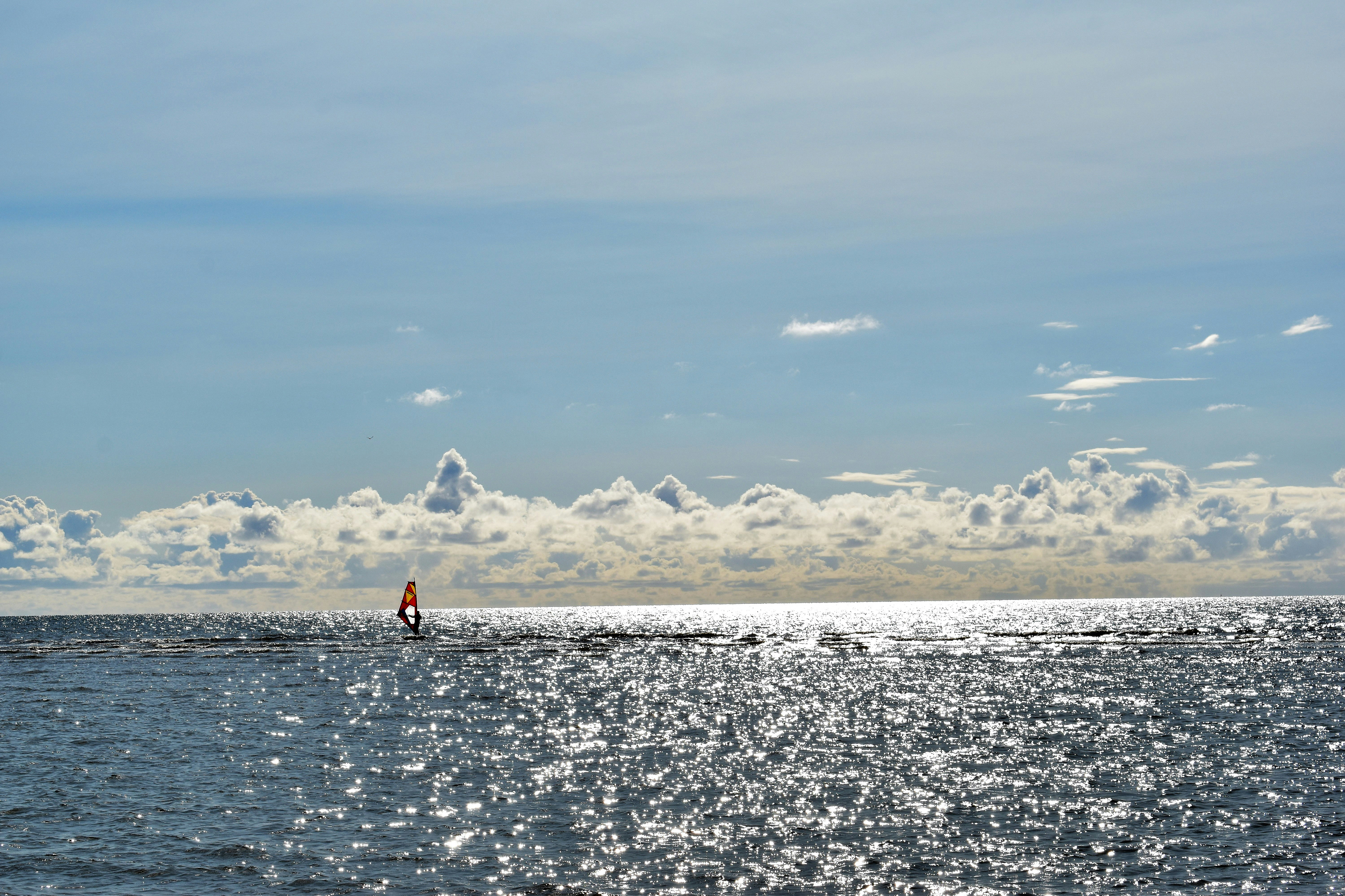 person in red shirt standing on sea shore during daytime