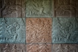 Stone carvings depict figures engaged in activities within a forested area, with intricate details showing trees and people carrying axes. The scene conveys a sense of historical or traditional craftsmanship.