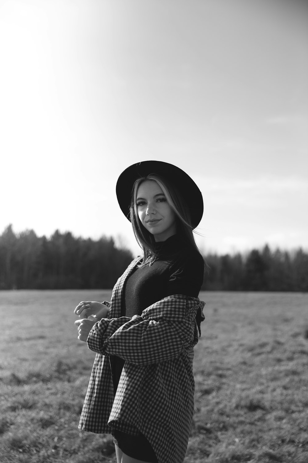 grayscale photo of woman in black hat and plaid long sleeve shirt