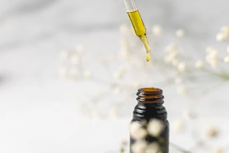Artistic close-up of golden serum drops falling from a dropper against a soft beige backdrop.