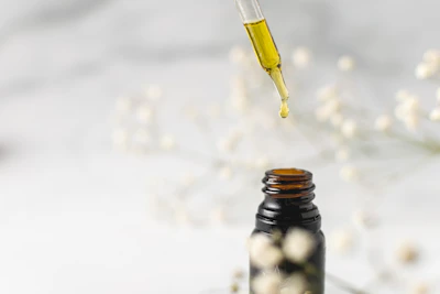Close-up of golden lemon essential oil drops glistening in a glass bottle.
