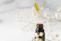 Close-up of a glass dropper releasing golden facial oil, set against a soft sage green background.