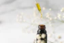 Close-up of a glass dropper releasing golden facial oil, set against a soft sage green background.
