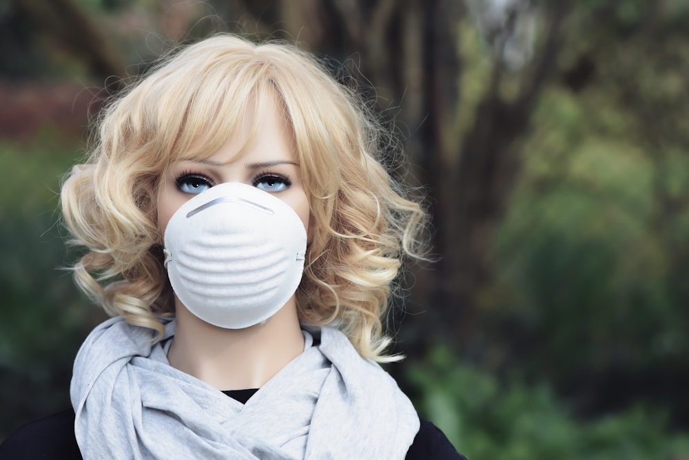 woman in gray coat covering face with white mask