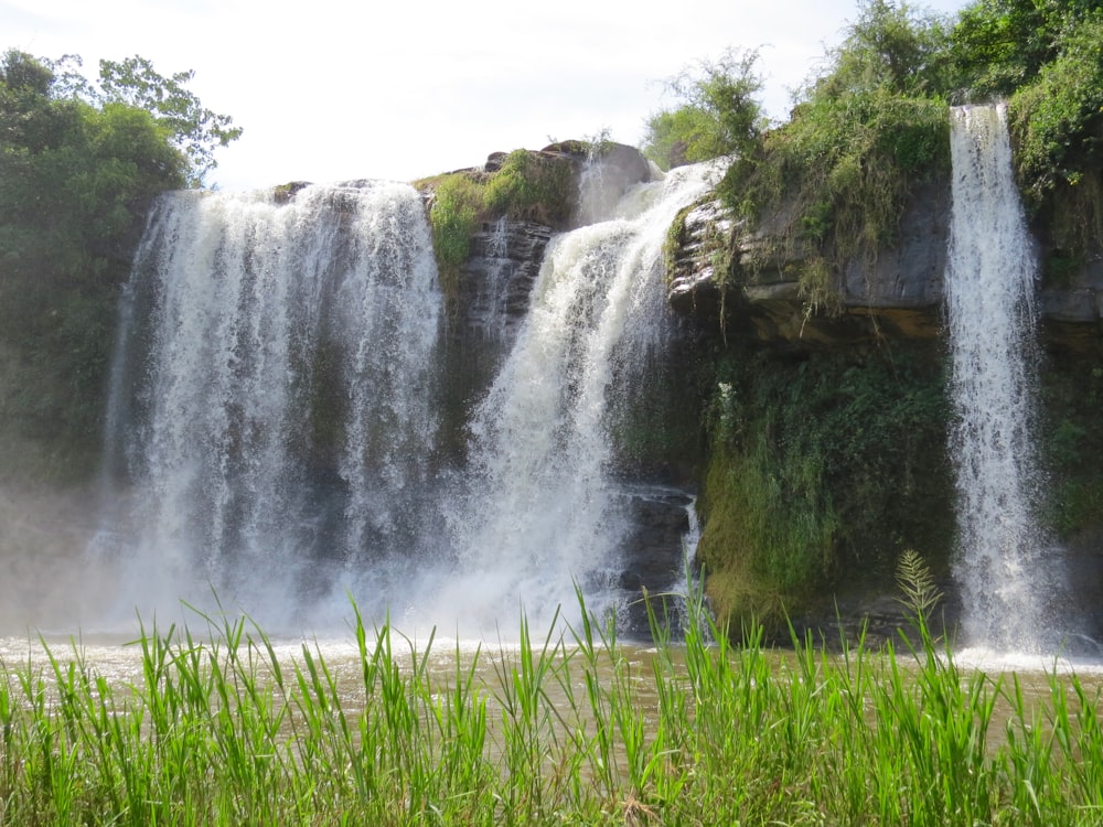 waterfalls in green grass field during daytime