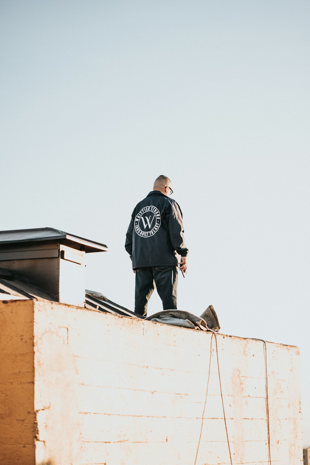 man in black jacket standing on top of building