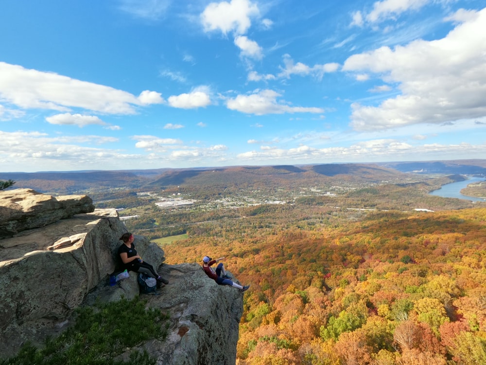 man in black jacket sitting on rock during daytime