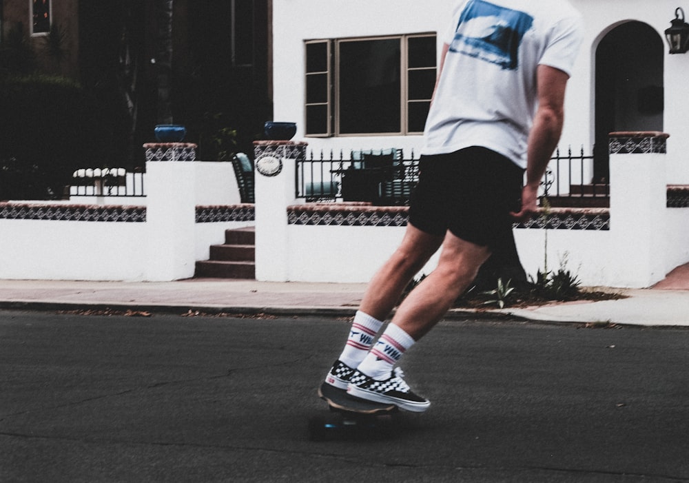 man in white t-shirt and black shorts running on road during daytime