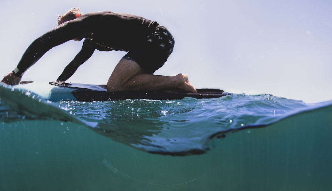 woman in black shirt and blue shorts sitting on water