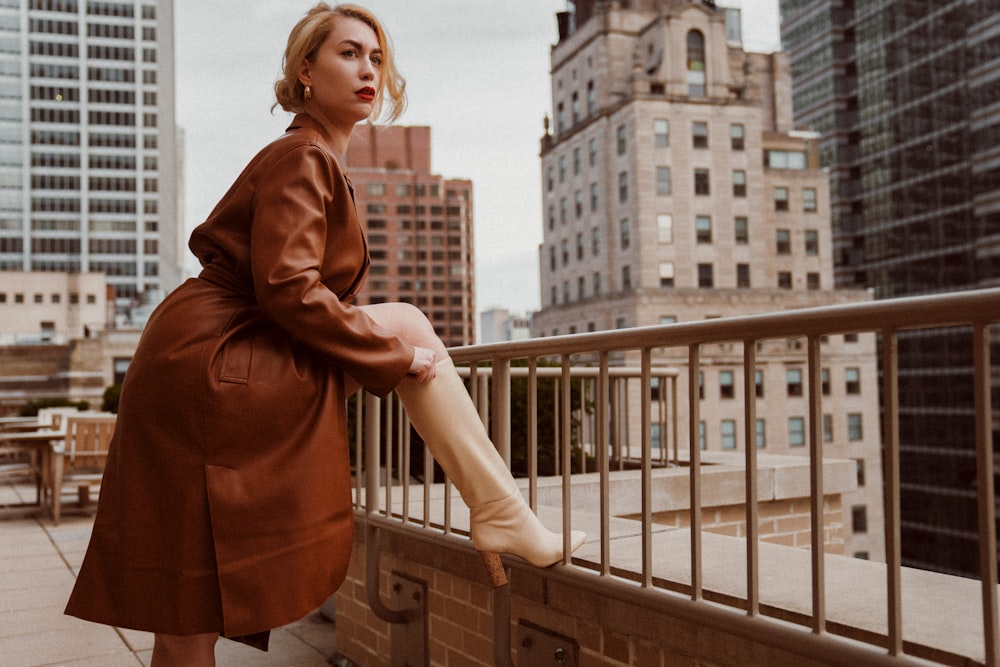 woman in brown coat standing on balcony during daytime