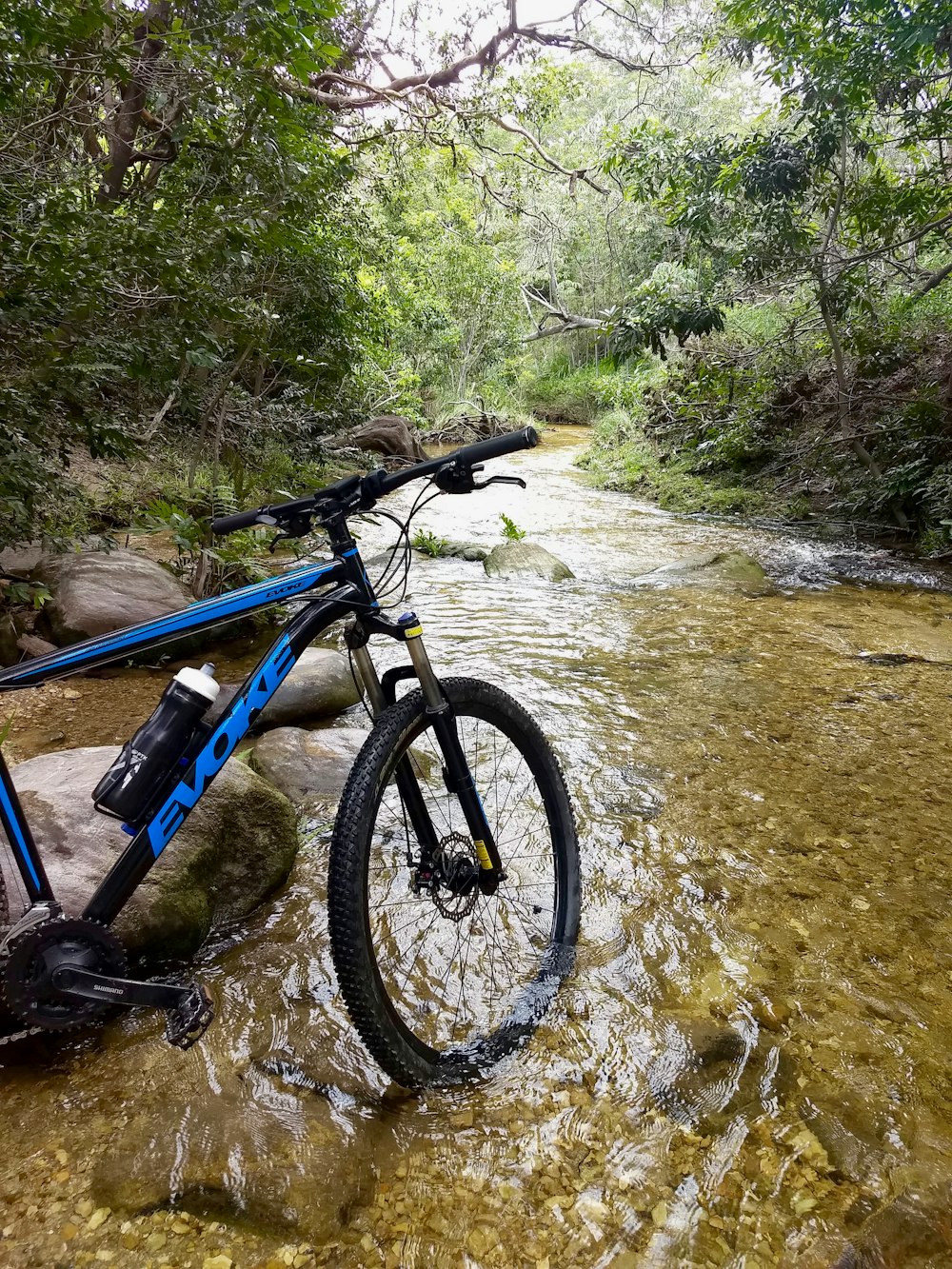 Bicicleta de montaña azul y negra en el río