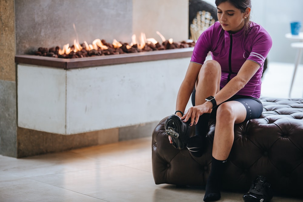 woman in purple crew neck t-shirt and black shorts sitting on white floor