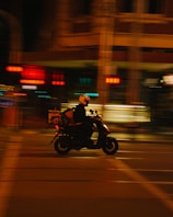 A delivery rider on a motorcycle navigating through Dubai city streets at sunset.