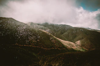 green and black mountains under white clouds during daytime