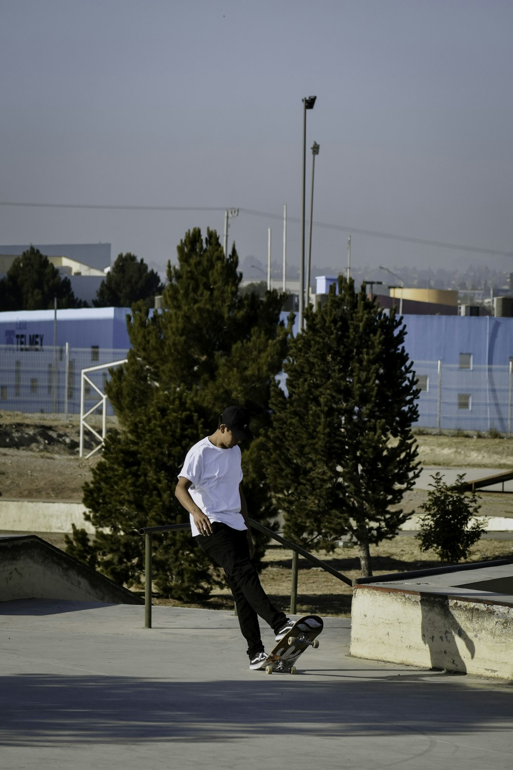 man in white t-shirt and black pants riding on black skateboard during daytime