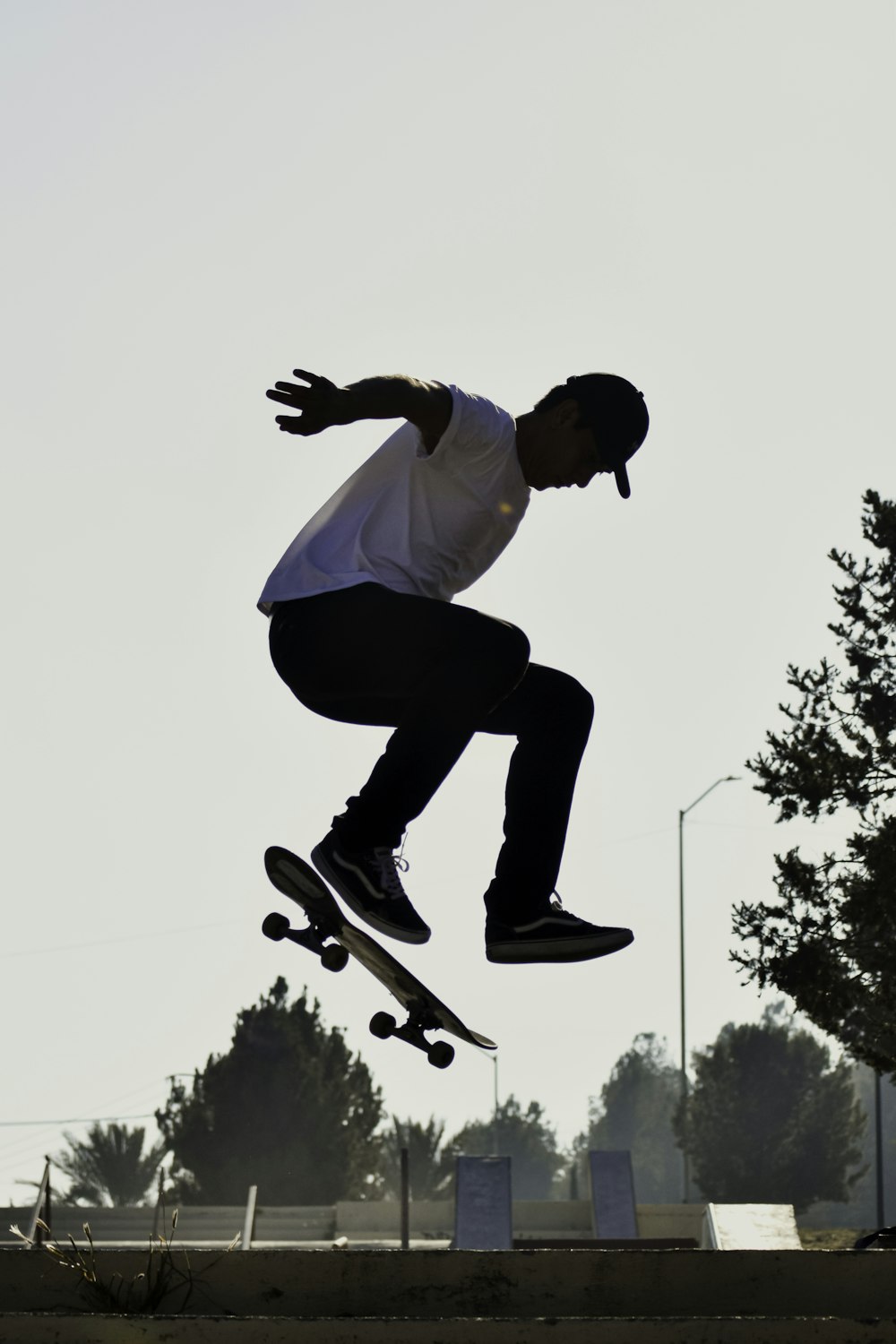 man in white shirt and blue pants doing skateboard stunts