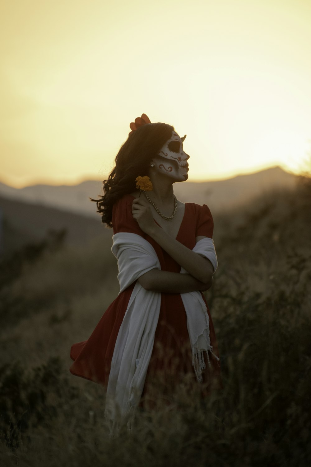 femme en robe blanche et rouge debout sur le champ d’herbe verte pendant la journée