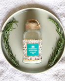 Elegant bottle of Rosmarin-Alkohol for skin wellness surrounded by fresh rosemary sprigs.
