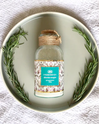 Elegant bottle of Rosmarin-Alkohol for skin wellness surrounded by fresh rosemary sprigs.