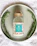 Close-up of a glass bottle of velora balsamic dressing with fresh herbs around it.