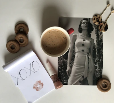 Styled flat lay of a personalized charm bracelet alongside a cup of coffee and a leather-bound notebook.