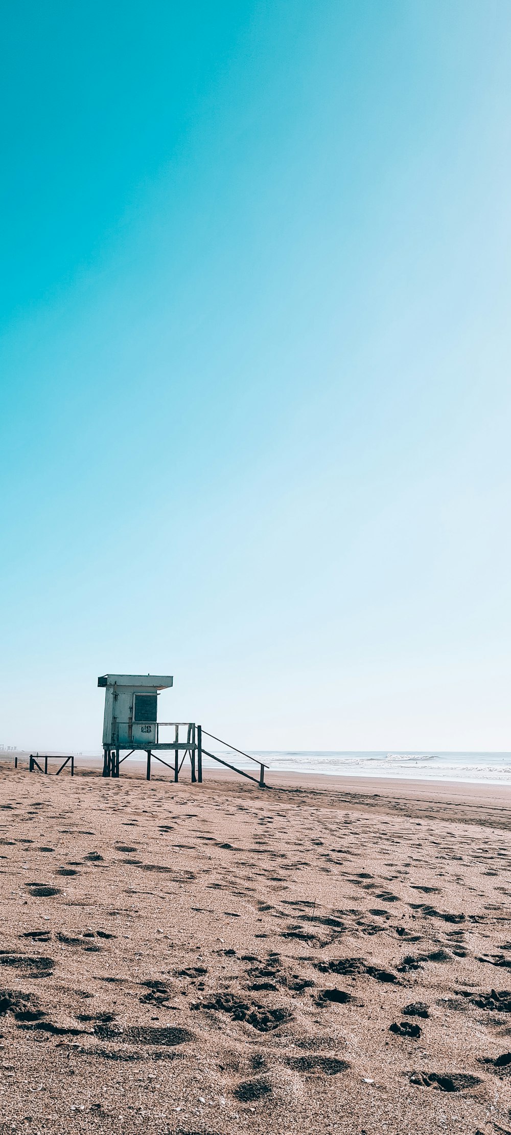 a lifeguard station on a beach with footprints in the sand