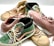 A collection of sneakers in various styles and colors displayed together, featuring textures like faux reptile skin and suede. The sneakers include high-top and low-top designs with detailed stitching and laces.