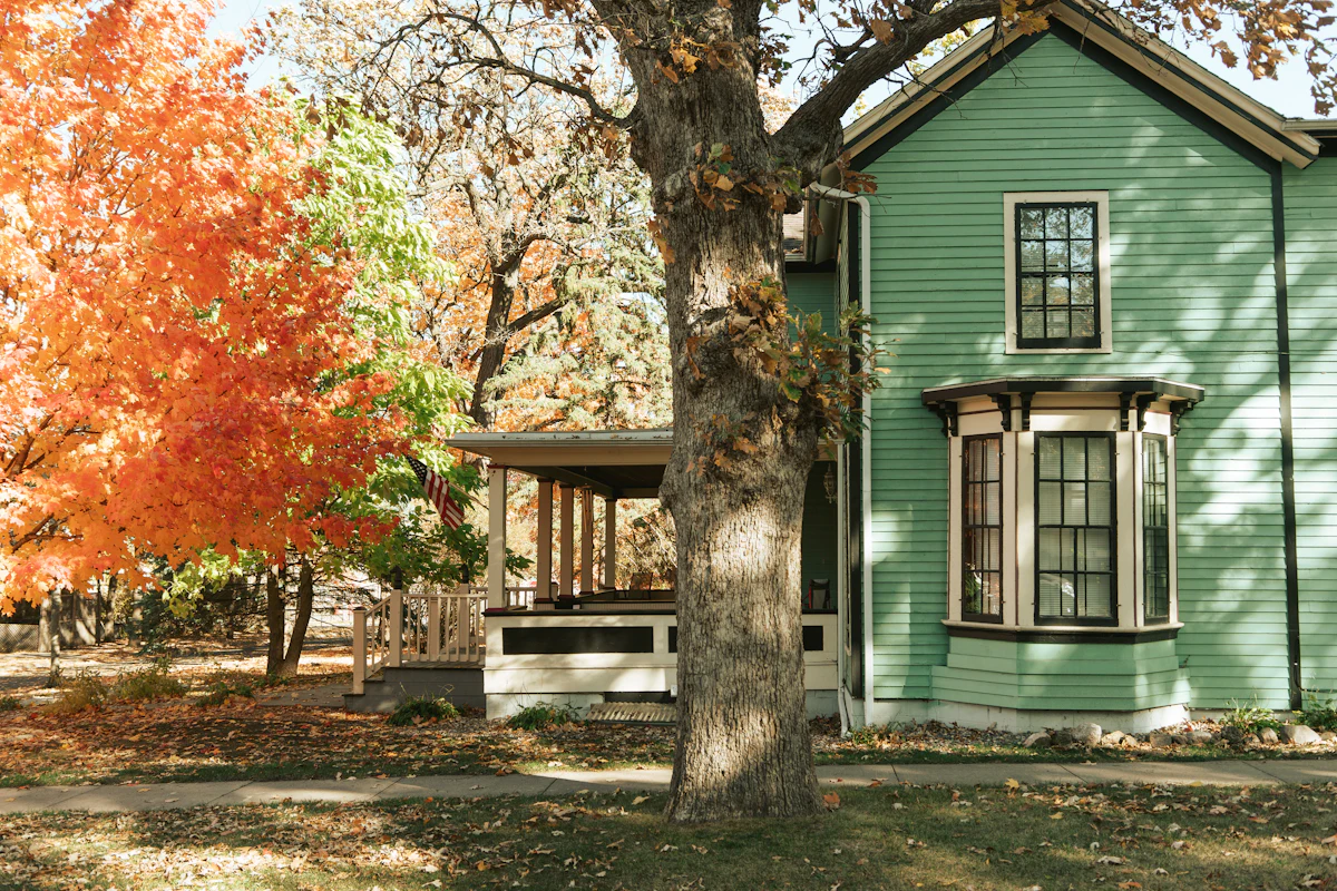 White wooden house beside a tree in fall color