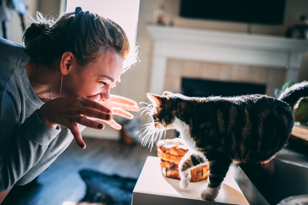 woman in gray sweater holding black and brown cat