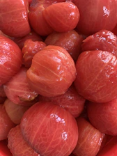 A close-up of a high-tech tomato processing machine in action, with ripe tomatoes being peeled and pulped.