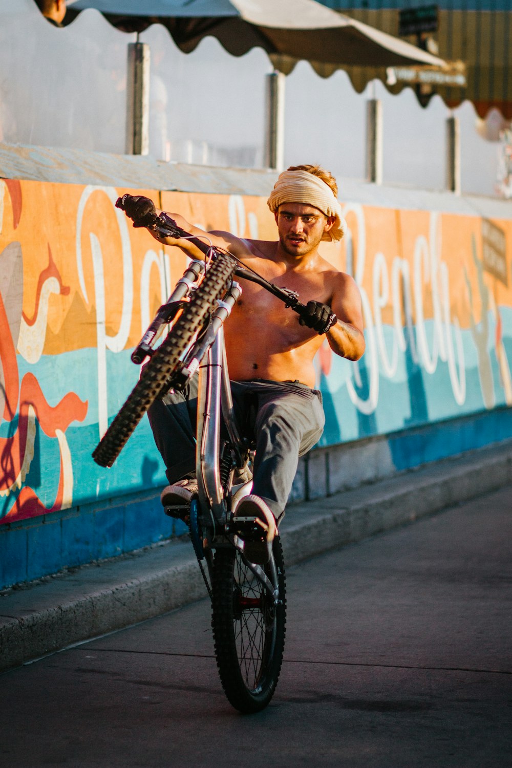 man in black tank top and gray pants riding bicycle