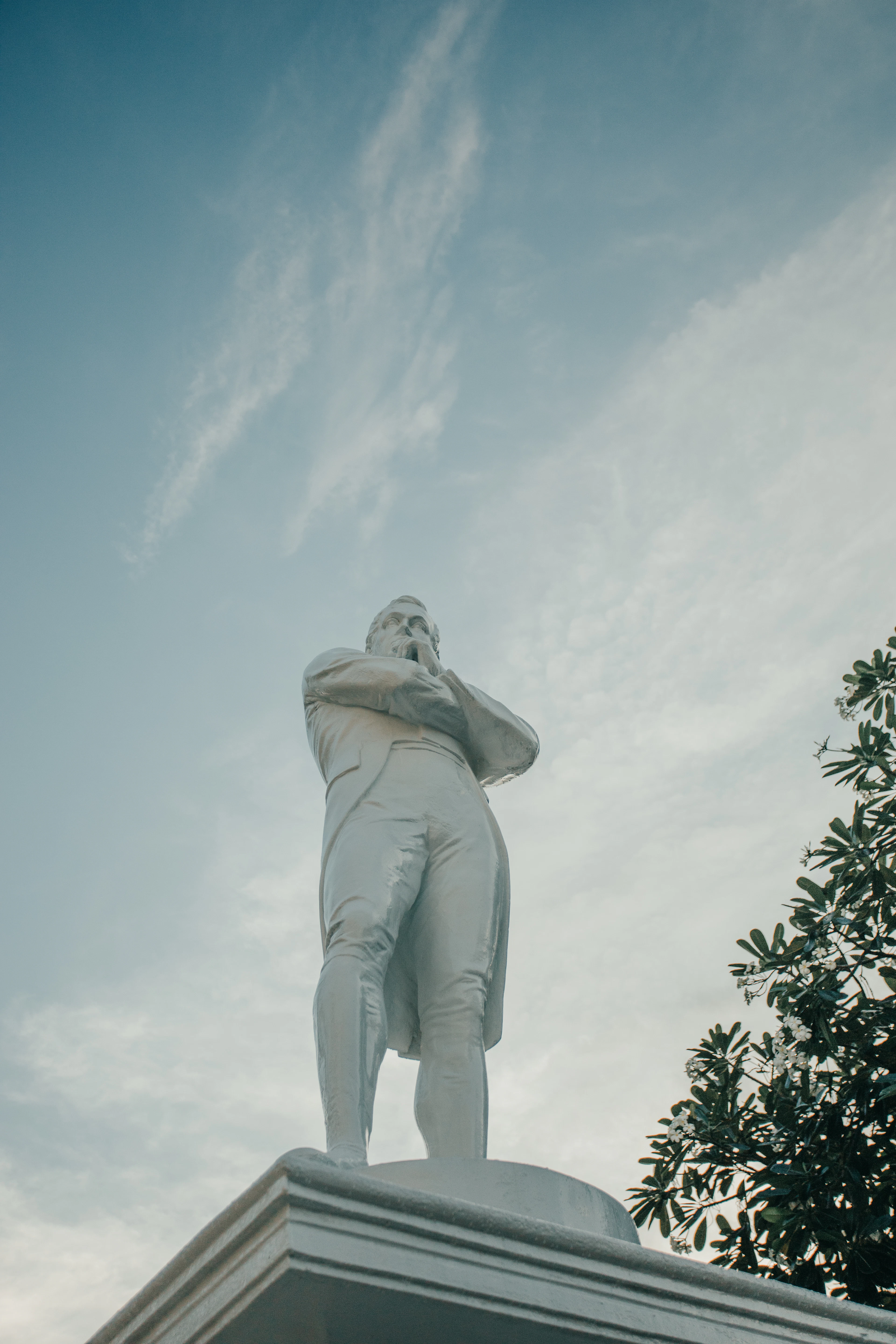 The white statue of Sir Stamford Raffles at the Raffles Landing Site, seen from below against a pale sky.