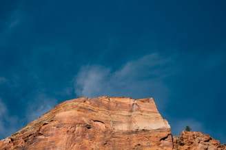 A geologist examining rock layers on a hillside with engineering tools nearby under a clear sky.