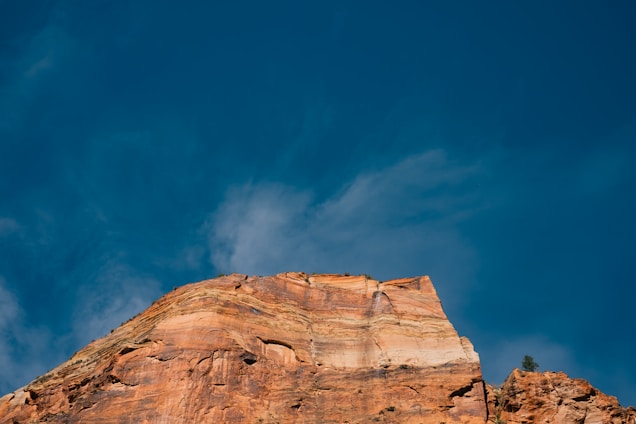 A geologist examining rock layers on a hillside with engineering tools nearby under a clear sky.
