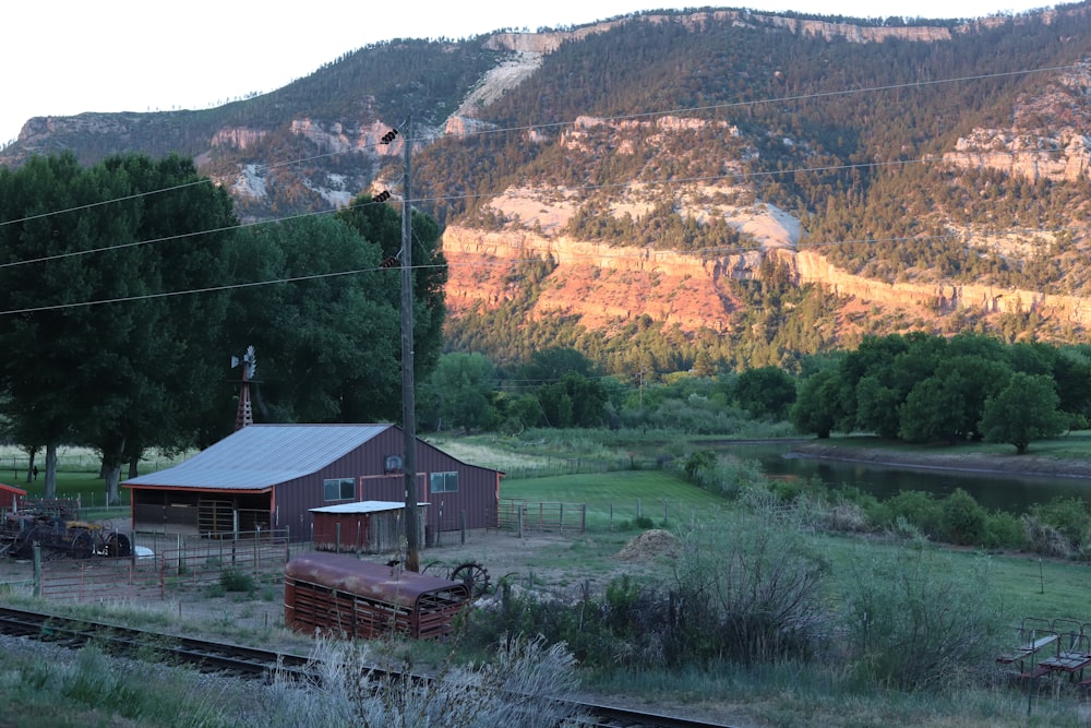 brown wooden house near green grass field and mountain during daytime