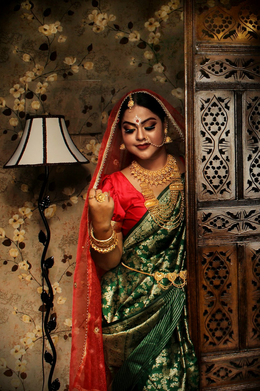 woman in green and red sari holding brown wooden door