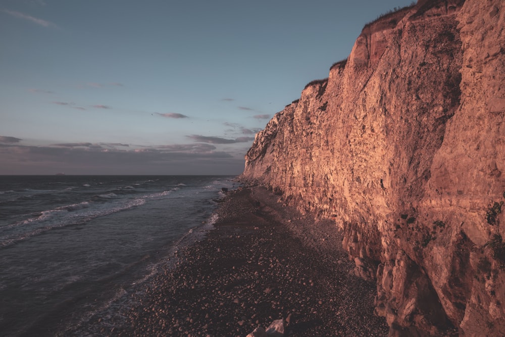 brown rock formation near body of water during daytime