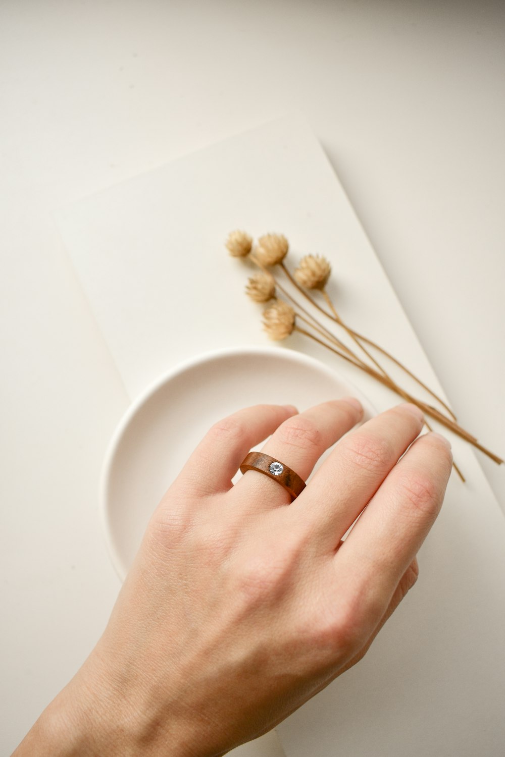 person wearing gold wedding band holding white ceramic plate