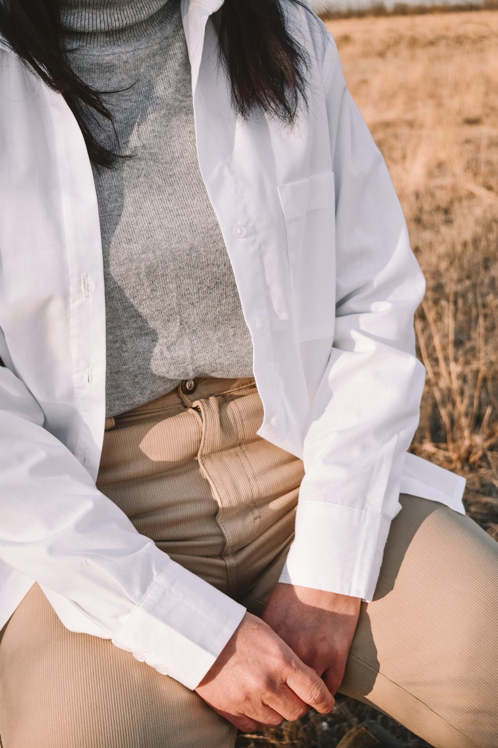 man in white button up long sleeve shirt and brown pants sitting on brown wooden bench