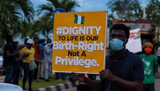 a man holding a sign that says dignity to life is our birth -