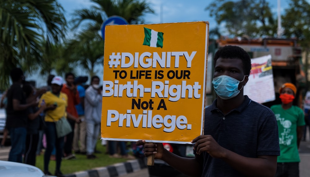 a man holding a sign that says dignity to life is our birth -