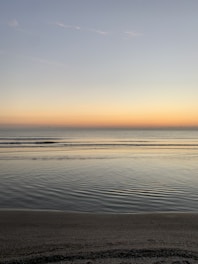 A serene illustration of soft waves gently lapping a quiet shore under a twilight sky.