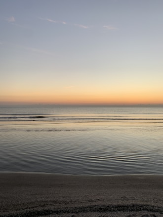 A serene illustration of soft waves gently lapping a quiet shore under a twilight sky.