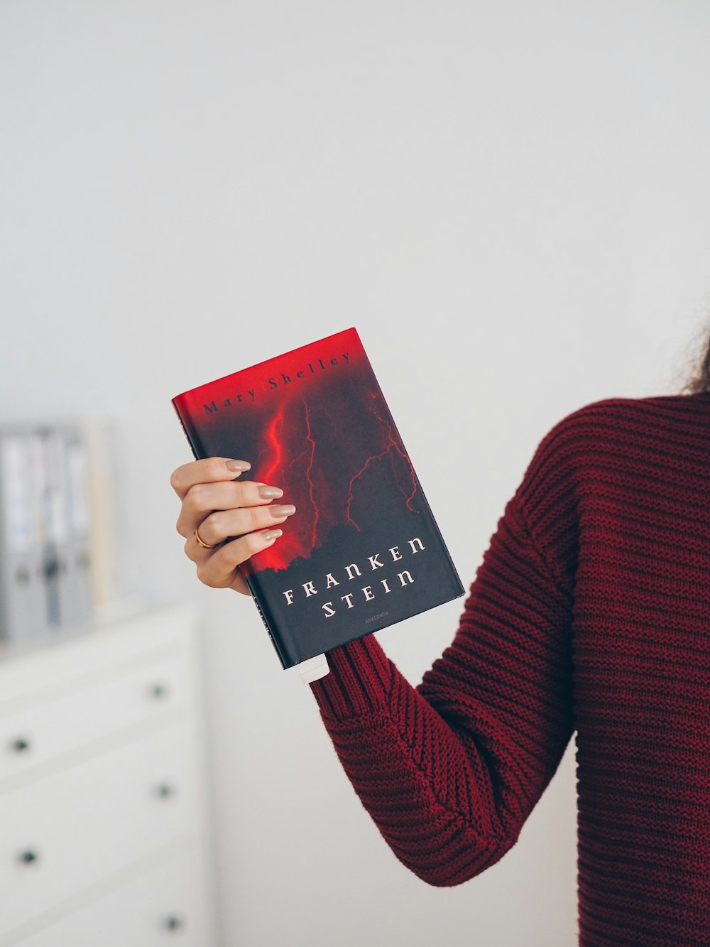 woman in red sweater holding red book